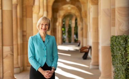UQ Vice-Chancellor Professor Deborah Terry encourages students to attend UQ's ATAR Advice online event. Woman in a blue jacket stands outside a shady sandstone building.